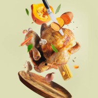 creative thanksgiving food with whole roasted turkey, sweet potato, knife, carrot, pumpkin, onion, garlic and herbs flying in the air over wooden plate at pale beige background. - food stock pictures, royalty-free photos & im
