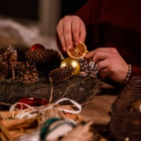 creative young man decorating a christmas wreath with rustic ornaments - home decoration stock pictures, royalty-free photos & images