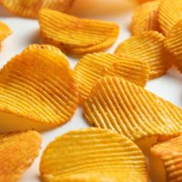 crispy fried potato chips are scattered on a white background or table. corn spicy fatty chips with paprika and spices. the concept of unhealthy diet and lifestyle, accumulation of excess weight. copy space. background of foo