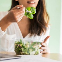crop view of young architect eating mixed salad at desk - junk food stock pictures, royalty-free photos & images