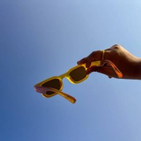 cropped hand holding sunglasses against blue sky background - fashion stock pictures, royalty-free photos & images