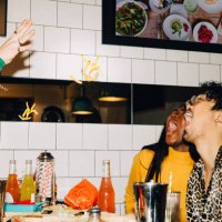 cropped hand of man throwing french fries at male and female friends with open mouth in cafe - food stock pictures, royalty-free photos & images