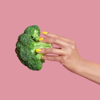 cropped hand of woman holding broccoli against pink background,kyiv,ukraine - food photos et images de collection