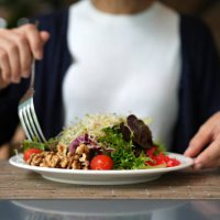 cropped image of woman having healthy green salad with alfalfa sprouts, cherry tomatoes, walnuts, leafy vegetables, olives, and salad dressing. - food stock pictures, royalty-free photos & images