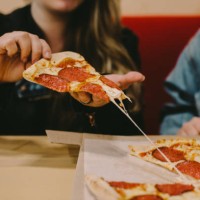 cropped image of woman holding pizza slice at restaurant - junk food stock pictures, royalty-free photos & images