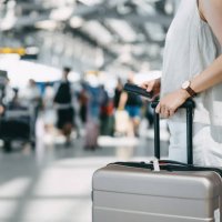 cropped image of young woman holding passport and suitcase walking in the international airport hall - travel stock pictures, royalty-free photos & images