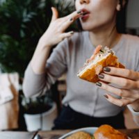 cropped shot, mid-section of young asian woman eating freshly made delicious cheeseburger in a cafe, licking her fingers. enjoying her lunch! people and food concept - junk food stock pictures, royalty-free photos & images