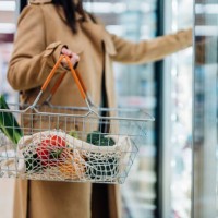 cropped shot of woman carrying shopping basket and shopping groceries in supermarket - food stockfoto's en -beelden