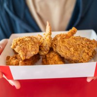 cropped shot of woman holding a paper box with pieces of fried chicken before eating. - junk food stock pictures, royalty-free photos & images