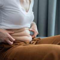 cropped shot of woman touching and squeezing her fat belly. - junk food stock pictures, royalty-free photos & images