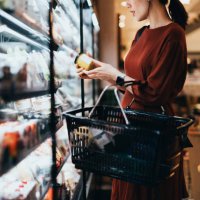 cropped shot of young asian woman carrying a shopping basket, standing along the dairy aisle, reading the nutrition label on the bottle of a fresh organic healthy yoghurt. making healthier food choices - food stock pictures, 