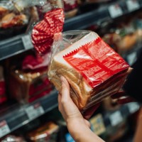 cropped shot of young asian woman grocery shopping in supermarket, shopping for fresh bakery and reading the nutrition label at the back of a packaged bread. routine shopping. healthy eating lifestyle - food photos et images 