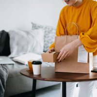 cropped shot of young asian woman holding boxes of home delivery takeaway food that have just arrived to share, serving on the coffee table. eating at home concept - junk food stock pictures, royalty-free photos & images