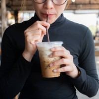 cropped shot view of young asian woman drinking iced milk coffee in coffee shop. - junk food stock pictures, royalty-free photos & images