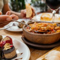 cuisine géorgienne traditionnelle. homme mangeant chashushuli végétarien aux champignons, avec phali - collation à base de noix, de divers légumes ou herbes et d’épices et de rouleaux d’aubergines, lobio dans un pot en argile
