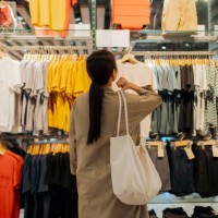 customer contemplating clothing choices in a fashion retail shop - fashion stock pictures, royalty-free photos & images