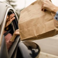 customer receiving coffee and takeaway food order from a service person at the drive through - junk food stock pictures, royalty-free photos & images
