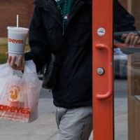 Customer with a takeout order exits a Popeyes fast food restaurant in the Queens borough of New York, US, on Sunday, Feb. 11, 2024. Restaurant Brands...