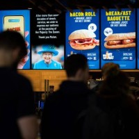 Customers queue beneath a tribute to tribute the late Queen Elizabeth II, at a fast food store inside King's Cross train station in London on...
