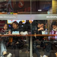 Customers sit at a window-facing table inside a McDonald's restaurant, eating and using their phones on February 12 in Chongqing, China.