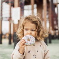 cute little girl biting sweet and tasty donut outdoors. unhealthy but delicious food - junk food stock pictures, royalty-free photos & images