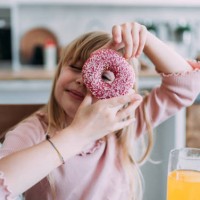 cute little girl looking through donut. - junk food stock pictures, royalty-free photos & images