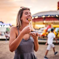 cute woman eating small donuts at the funfair - food stock pictures, royalty-free photos & images