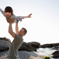 dad lifts young son above his head on beach - travel stock-fotos und bilder