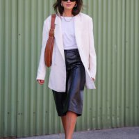 Darja Barannik wears. Black sunglasses, white necklace, white t-shirt, cream oversized blazer jacket, light brown leather bag, shiny black leather...