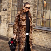 Darja Barannik wears black top, black pants, animal print coat, black bag with accessories outside the Munthe fashion show during the Copenhagen...