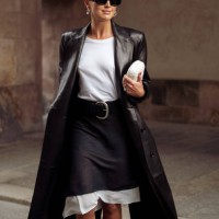 Darja Barannik wears grey and white midi skirt, white top, black long leather coat, black leather belt, white bag, sunglasses outside the Rotate show...