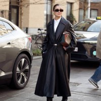 Darja Barannik wears white shirt, long black leather coat with golden button and brown and green LOEWE bag outside A. Roege Hove show during the...