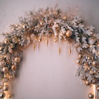 decorated christmas arch with snow-covered fir branches and gold toys: balls and icicles in sparkles. white, silver, grey and golden colors. concept of new year and christmas coming. new year's decorations for photo shoots an