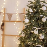 decorated christmas tree with white ornaments and lights in cozy room with white wall. - home decoration stock pictures, royalty-free photos & images