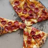 delicious italian pizza in a pizza box and a delivery box, on the table in a pizzeria. sliced pizza slice with tomatoes, pepperoni sausage and cheese. the concept of unhealthy lifestyle, overeating, junk food, fast food. deli