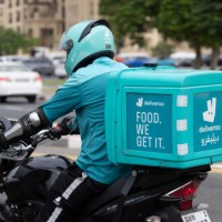 Deliveroo delivery driver on a motorbike waiting in traffic in Dubai, United Arab Emirates on the 26th of October 2023.