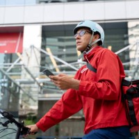 delivery man pushing bicycle and checking directions on smartphone - junk food stock pictures, royalty-free photos & images