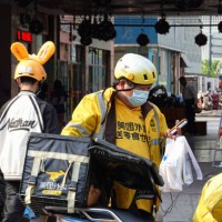 Delivery man wearing a face mask as a preventive measure against the spread of coronavirus holds some takeaway drinks in his hand. The mask mandate...