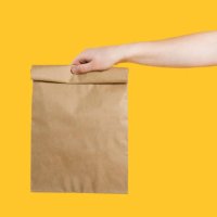 delivery service service concept. male hand holding eco craft takeout food bag on isolated yellow background studio. packaging mock up template. copy space - junk food stock pictures, royalty-free photos & images