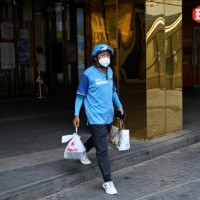 Delivery worker carries a take-away food order outside a mall in Beijing on June 20, 2022.