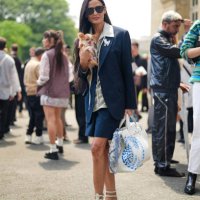 Demi Moore wears black sunglasses, silver necklace, gray v-neck oversized shirt, black oversized blazer jacket, black mini skirt, white striped...