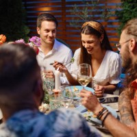 des amis joyeux qui parlent tout en dînant à table à manger en fête - garden decoration photos et images de collection