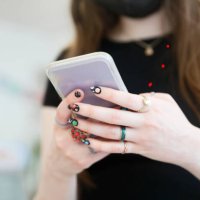 detail of a woman's hands using a cell phone, decorated with rings and painted nails of the solar system. - nails art stock pictures, royalty-free photos & images