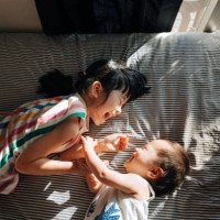 directly above shot of happy little asian girl and her baby sister having fun together and playing on the bed, both of them are smiling joyfully. siblings love. love, bonding and togetherness - home decoration stock pictures,