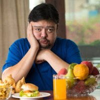 displeased man with unhealthy and healthy food on table - junk food stock pictures, royalty-free photos & images