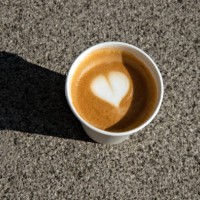 disposable cardboard cup of flat white coffee, with heart shape latte art, on a concrete pavement - junk food stock pictures, royalty-free photos & images