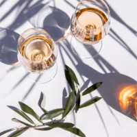 drinking rose wine glasses on white table with olive branch and palm leaf shadow - food stockfoto's en -beelden