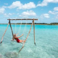 drone view of young woman having fun on swing in a beautiful lagoon on a sunny day - travel stock pictures, royalty-free photos & images