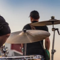 drummer sitting at a drum set and lead guitarist on stage as fireworks are shot off at the start of a live independence day concert - concert stock pictures, royalty-free photos & images