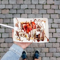 eating belgian waffle with sweet toppings and fresh fruits at the town square, personal perspective view - junk food stock pictures, royalty-free photos & images